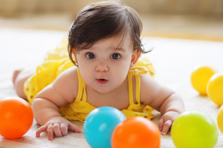 A happy baby surrounded by colourful play balls
